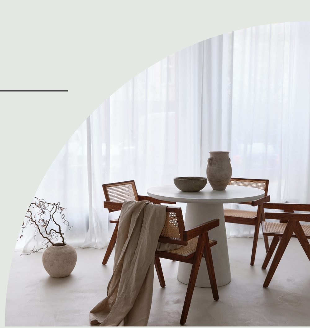 Dining nook with cane-back chairs, round pedestal table and sheer curtains