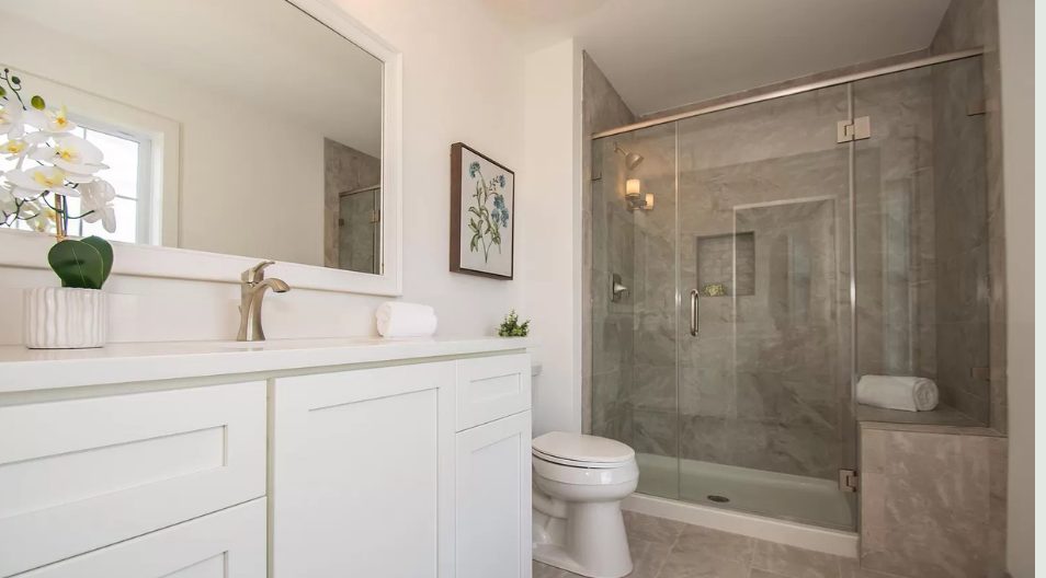 Bathroom with marble-tiled glass shower, white vanity and orchid