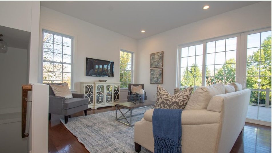 Bright living room with cream sofas, patterned pillows and wall of windows